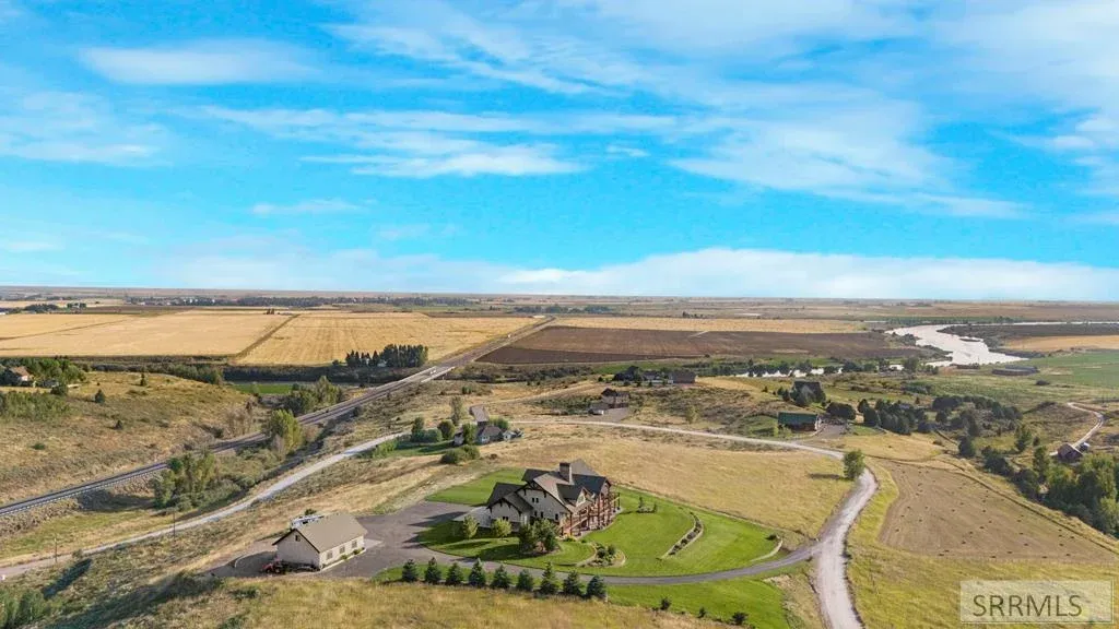 An aerial view of a country home, circular drive, and surrounding East Idaho fields